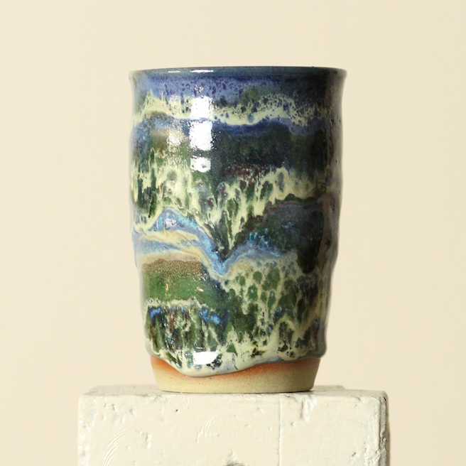 Ceramic tumbler with multicolored glaze on a beige background