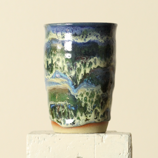 Ceramic tumbler with multicolored glaze on a beige background