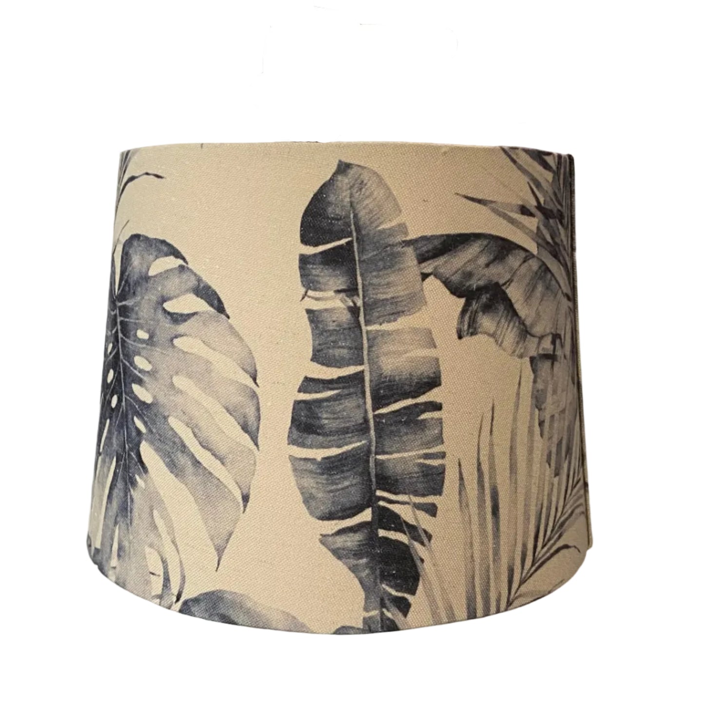 Lampshade with leaf pattern hanging against a textured wall.