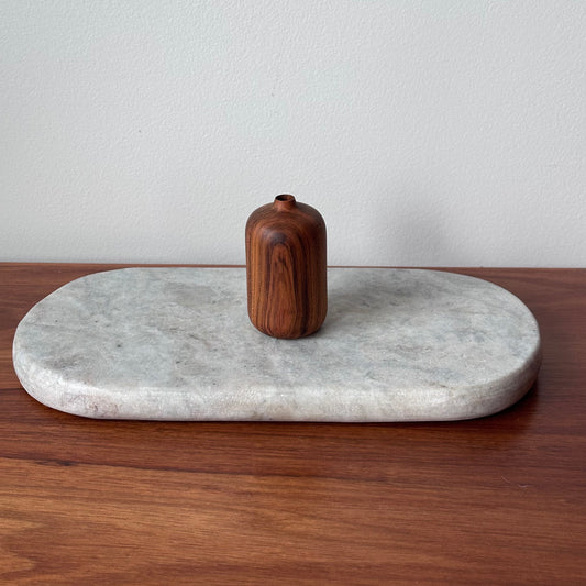 Marble tray with a wooden vase on a wooden surface