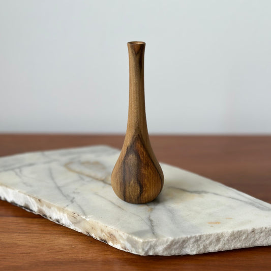 Wooden vase on a marble slab with a wooden surface underneath