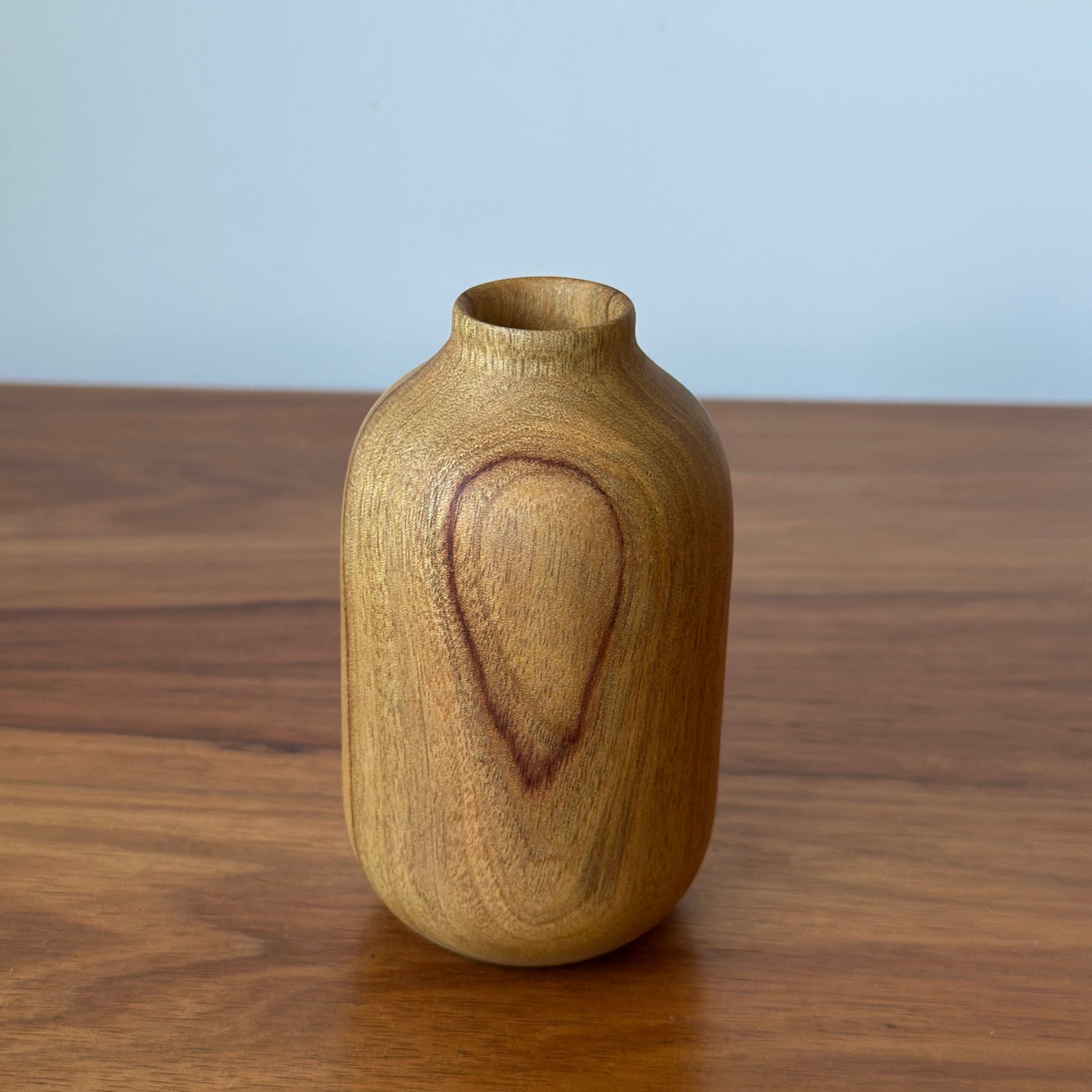 Wooden vase on a wooden surface with a light blue background