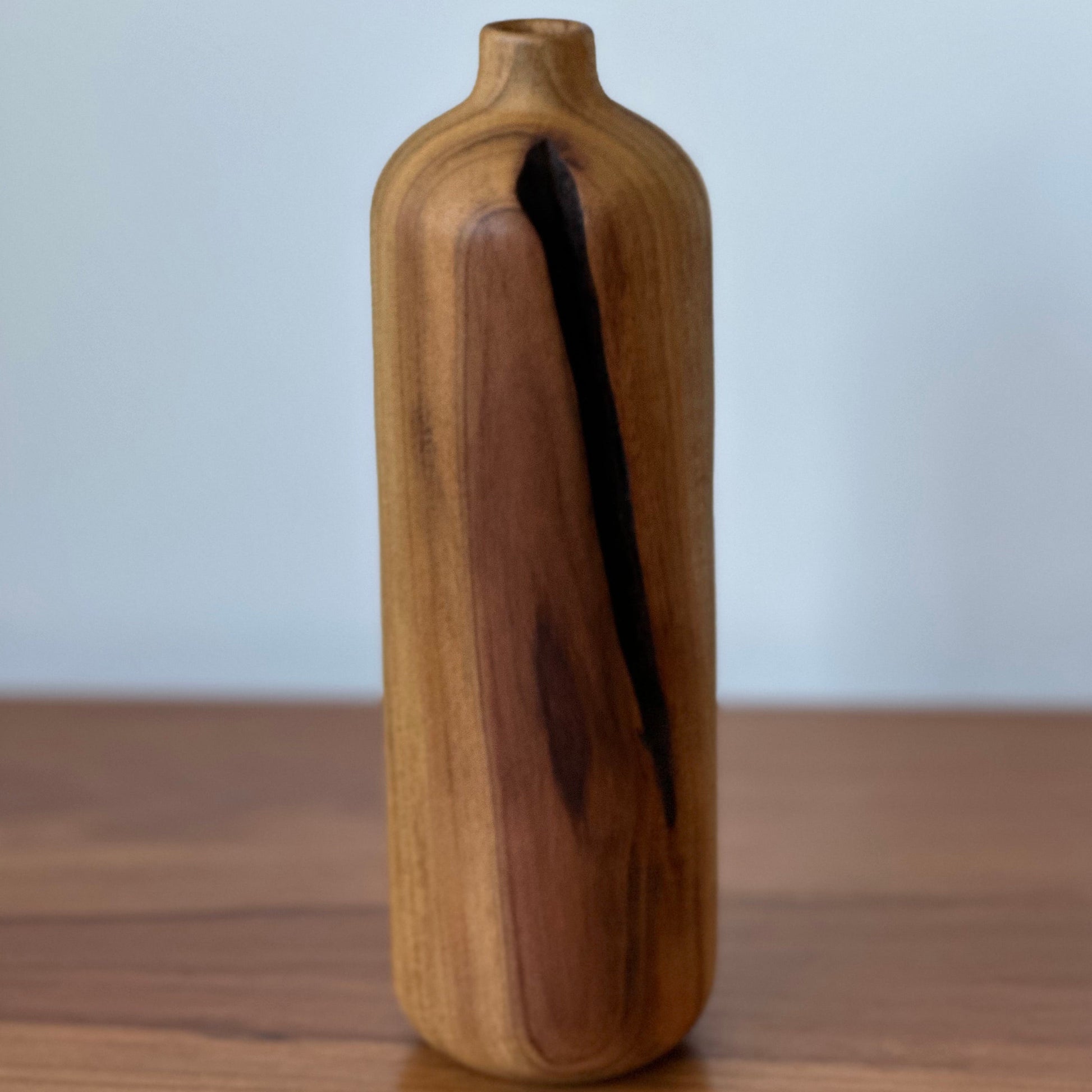 Wooden vase on a wooden surface with a light blue background