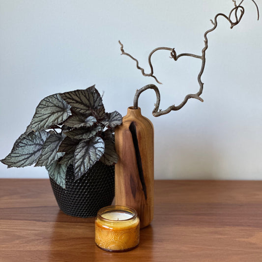 Decorative items including a plant, candle, and vase on a wooden surface.