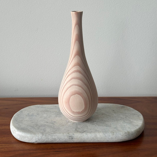 Decorative vase with wavy pattern on a marble base against a plain background