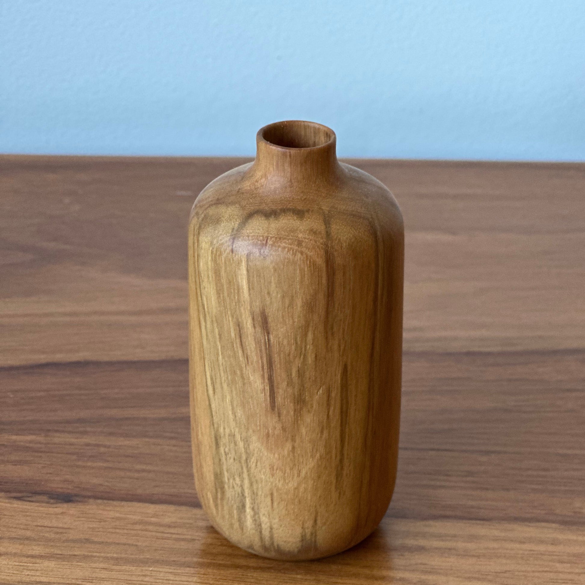 Wooden bottle on a wooden surface with a light blue background