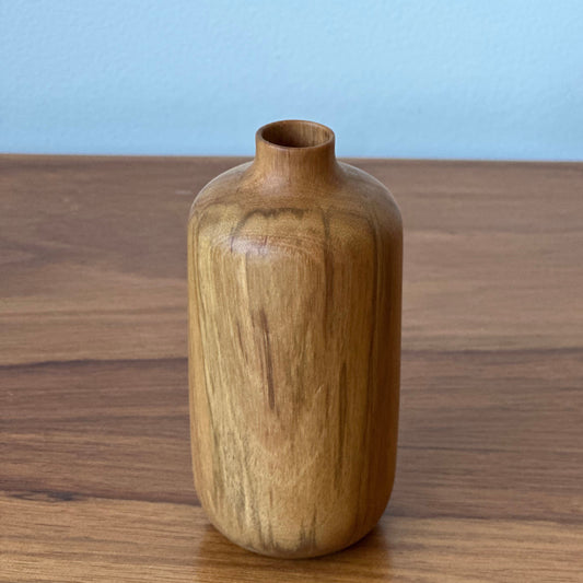 Wooden bottle on a wooden surface with a light blue background