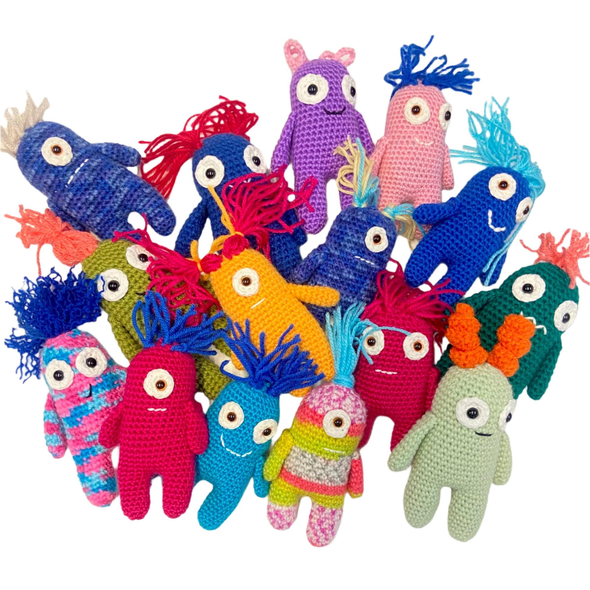 A collection of colorful handmade crochet worry monsters in various sizes and colors, each with a unique facial expression and hairstyle.