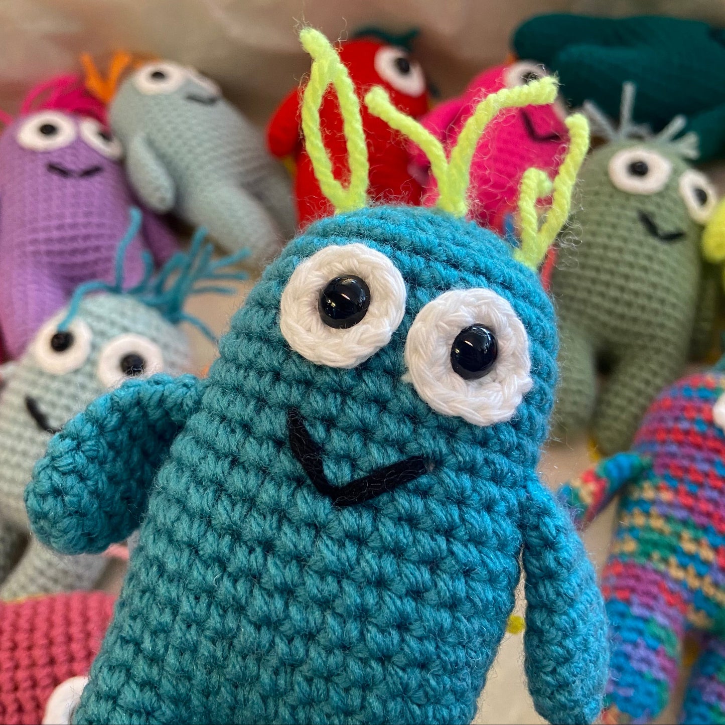 Colorful crochet monsters with a blue one in the foreground.