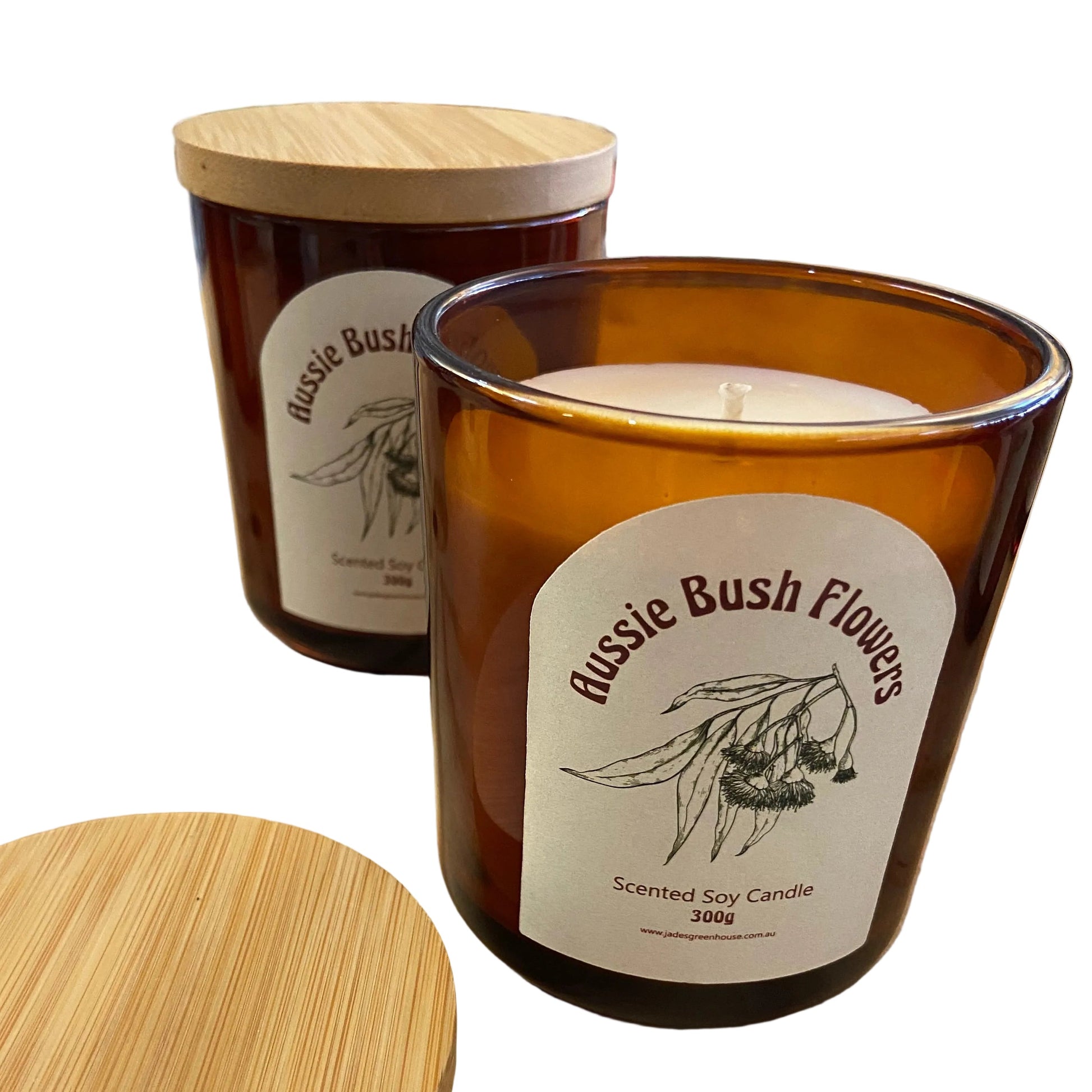 Two amber glass scented soy candles with bamboo lids on a wooden tabletop. The front candle is open, showing the white wax, and the back candle is closed.