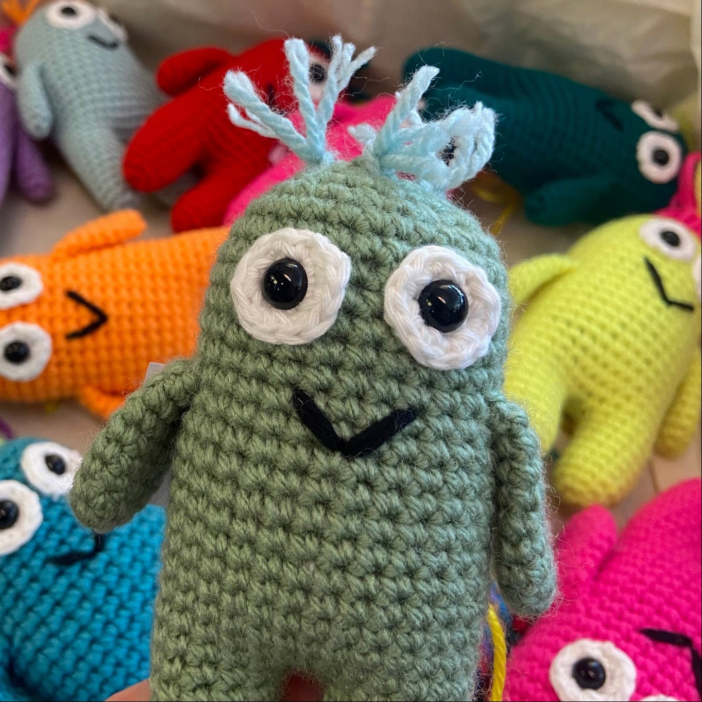 Colorful crochet monsters with a green one in the foreground.