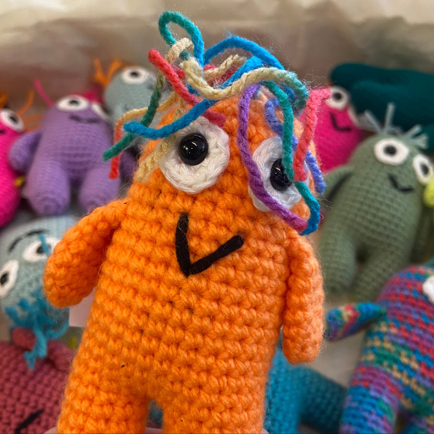 Colorful crochet monsters with an orange one in the foreground.