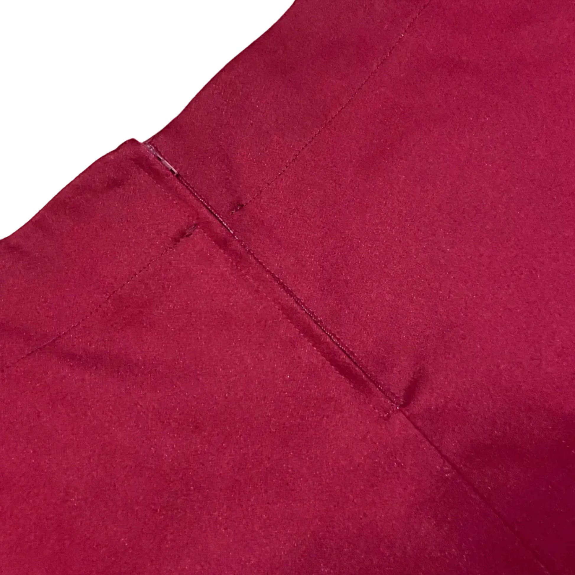 Close-up of a deep magenta or burgundy fabric surface with visible stitching and texture against a white corner background.