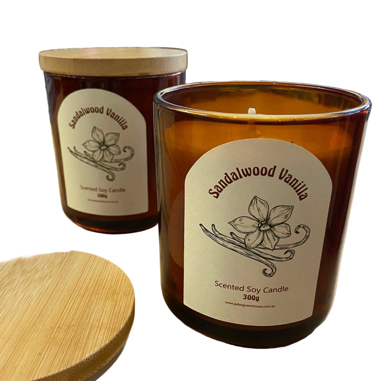 Two amber glass scented soy candles labeled Sandalwood Vanilla with light wood lids, displayed on a wooden table inside a candle store.