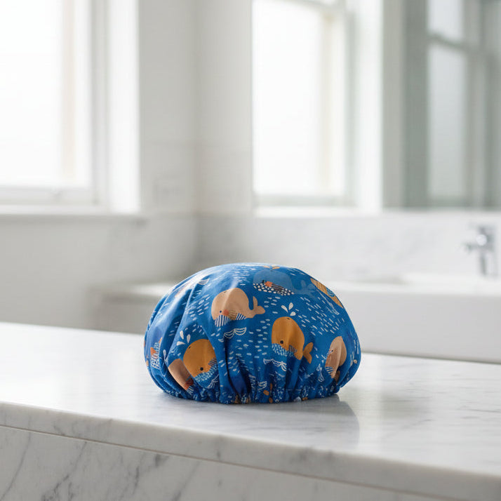 Blue shower cap with whale pattern on a mannequin head in a workshop setting
